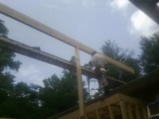 Carpenter setting a ridge beam over a new addition frame — Ice Dam Removal by Roofing Brothers in Cedar Bluffs
