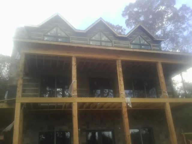 Dormers and porch framing on a large log home under construction — Roof Coating work by our crew in Cedar Bluffs