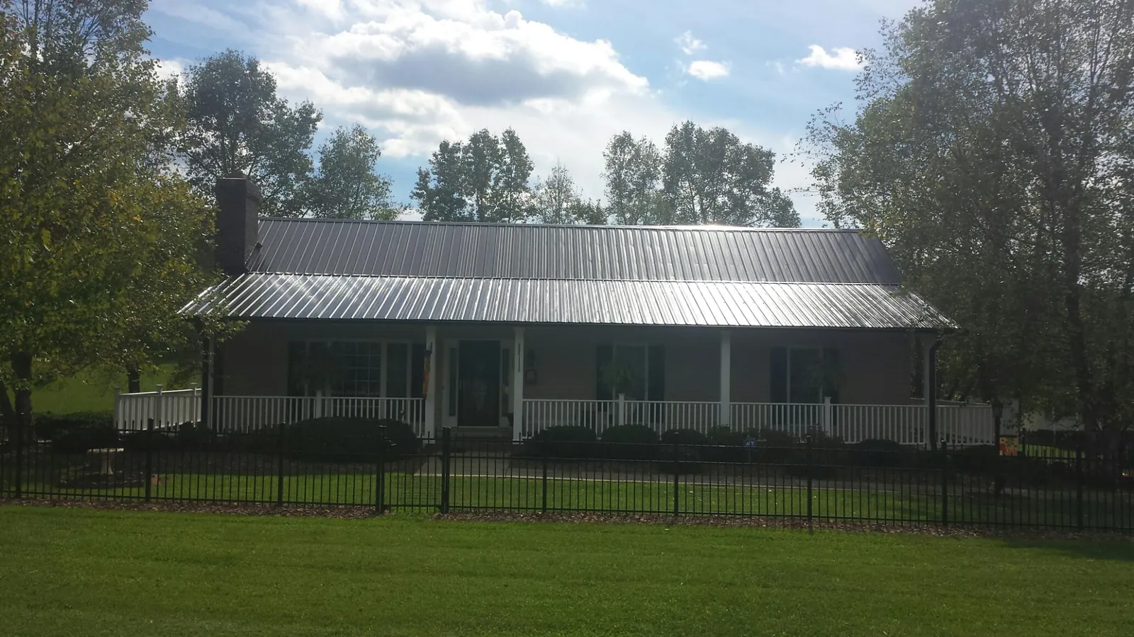 Gray metal roof on a brick ranch with a full width front porch — Gutter Guard Installation work by our crew in Cedar Bluffs