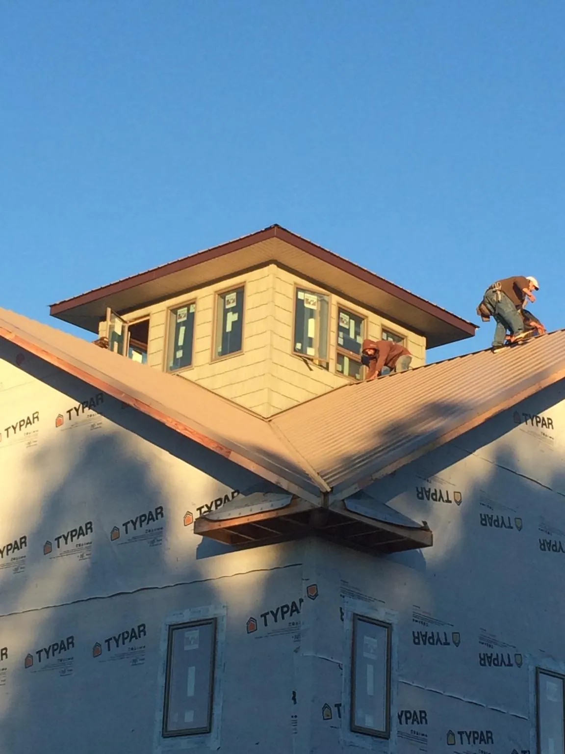 Roofers working around a rooftop cupola on a new metal roof at sunset — Roof Waterproofing in Cedar Bluffs by Roofing Brothers